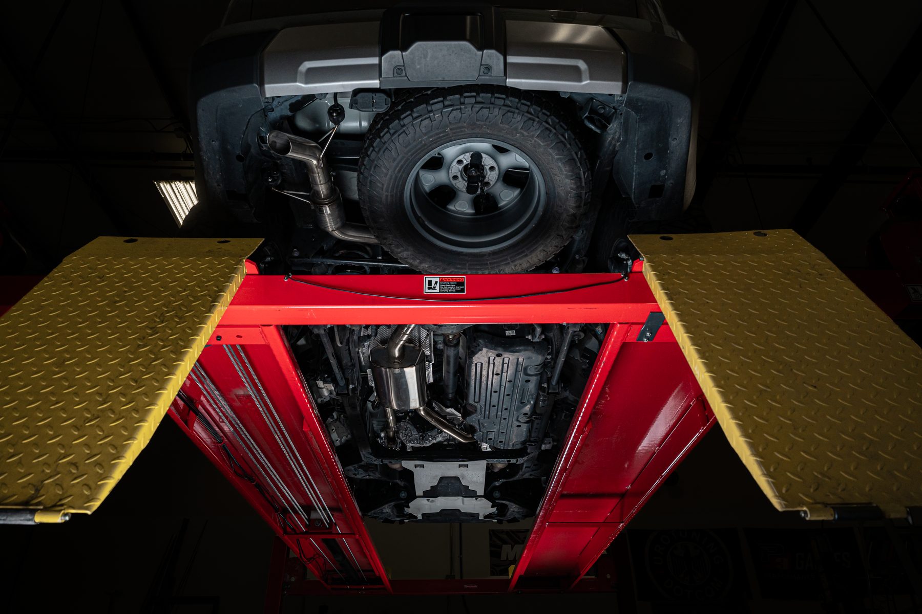 Milltek High Clearance cat-back exhaust SSXTY252 installed on a Lexus GX 550, viewed from below on a lift